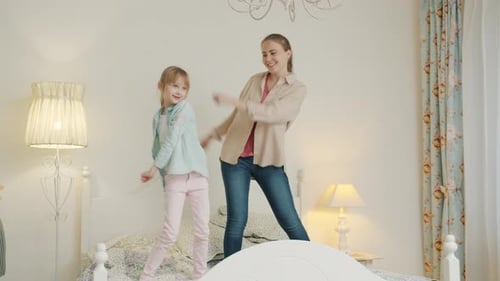 Happy Mother and Child Dancing on Bed