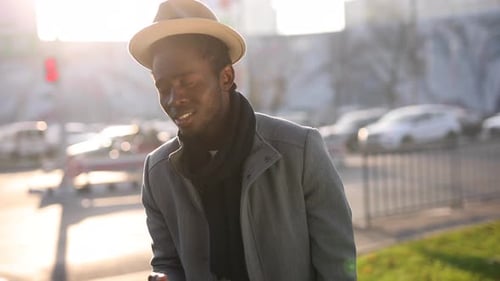 Happy African Man Plays with Hat in a City