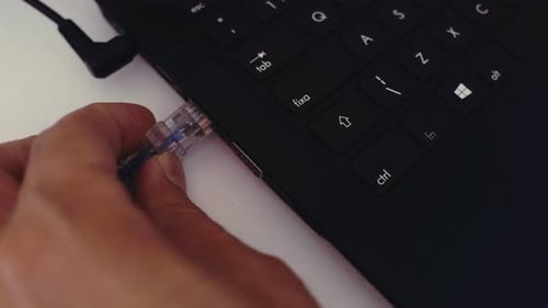 Close-up de um trabalhador de escritório conectando um cabo USB a uma porta USB em um laptop preto