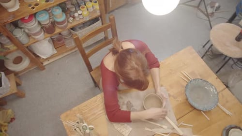 Red-Haired Woman Shaping Clay Bowl in Pottery Studio