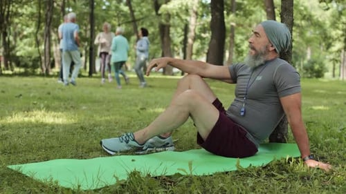 Senior Man Relaxing After Exercise Class in Park