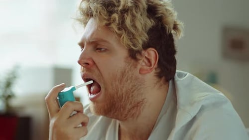 Homme malade qui tousse et utilise un spray pour la gorge