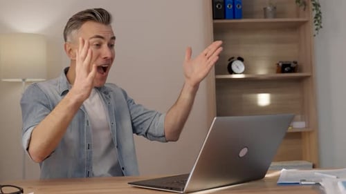 Excited Man Reacts Positively to Laptop at Home