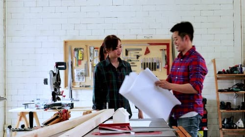 Two attractive Carpenter designing and discussion together with the blueprint in wood workshop
