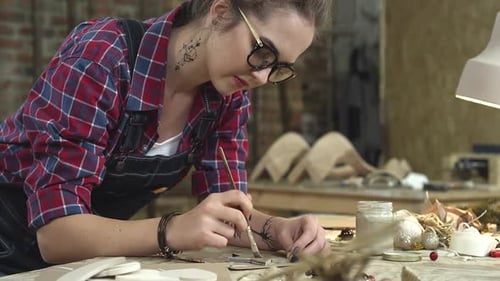 Junge Hipster malt handgefertigte Waren in ihrem Atelier