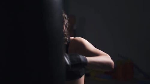 Young Woman in Boxing Gloves Training with a Punching Bag in a Boxing Club