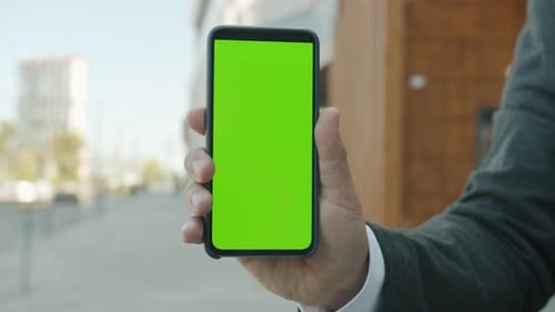 Closeup of Businessman's Hand Holding Chroma Key Green Smartphone Screen Outdoors in City