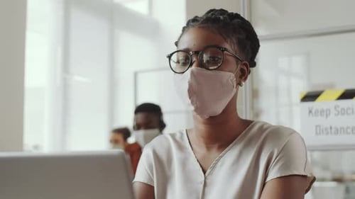 Afro-American Woman in Face Mask Working on Laptop in Office