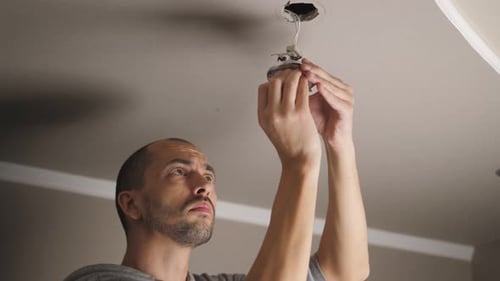 Man Installing New Light Fixture on Ceiling