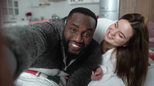 Smiling Couple Taking a Selfie in Bed at Home