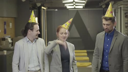 Mulher caucasiana positiva mostrando movimentos de dança para seus colegas do sexo masculino no espaço de coworking. Alegre