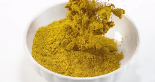Curry Powder falling into a Bowl against White Background, Slow motion 4K