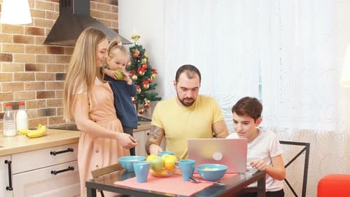Belle famille caucasienne à la maison regardant des vidéos sur un ordinateur portable à Kithen