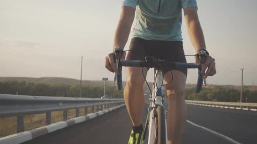 Nahaufnahme des gekrümmten Lenkrads eines Rennrads, die Hände eines Radfahrers beim Schalten der Geschwindigkeit