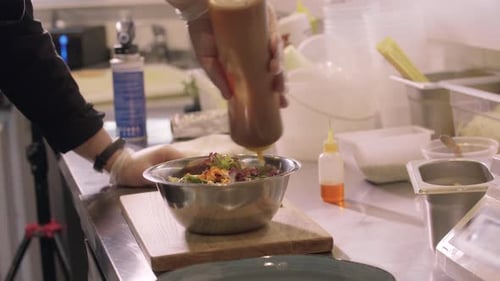 Un chef cuisinier ajoute de la sauce à une salade de citrouille