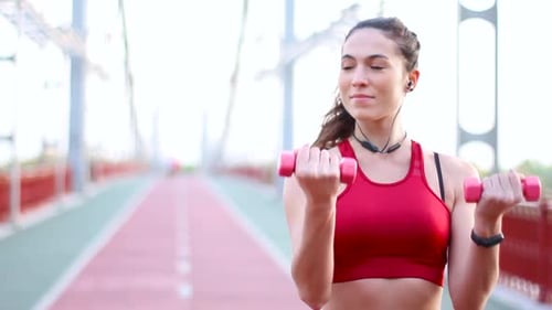 Woman Exercises with Dumbbells on Urban Pedestrian Bridge