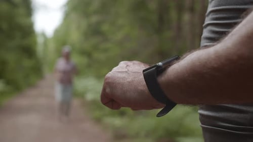 Senior Checks Fitness Watch in Forest