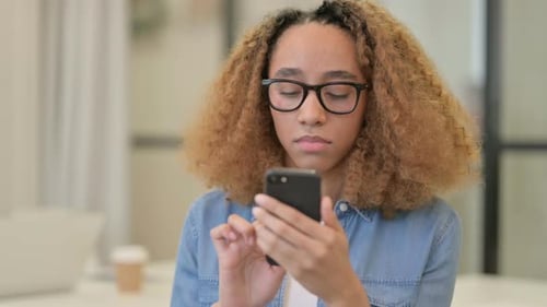 Young Woman Using Smartphone and Smiling Indoors