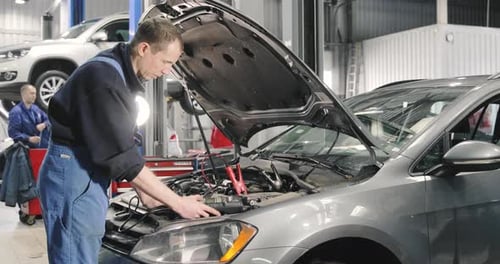 Mechanic Repairs Car Engine in Automotive Shop