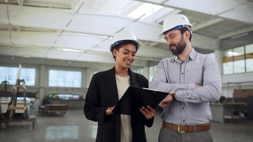 Smiling Engineers Reviewing Plans in a Bright Warehouse