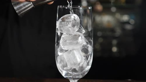 Pouring Drink into Icy Glass in Bar Setting
