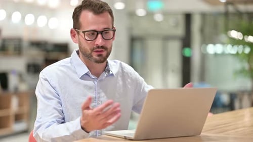 Businessman Talking on Video Call on Laptop in Office