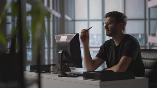 Ein ernsthafter Mann sitzt im Büro an einem Computer und denkt