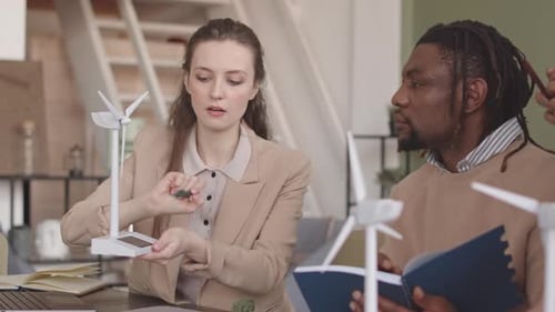 Team Discussing Renewable Energy with Wind Turbine Models