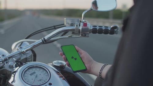 man on motorcycle looks at his phone the road. Side view of the hands of man sitting modern motorcyc
