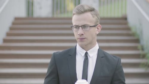 Young Man in Suit with Coffee Checks Watch