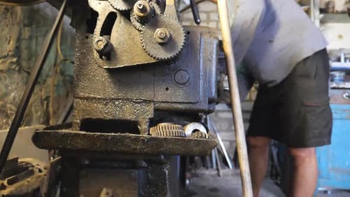 Adult Man Working with Workbench in His Garage or Workshop. Mechanic or Turner Using Lathe for Metal