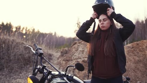 Woman Puts on Motorcycle Helmet in Rural Setting