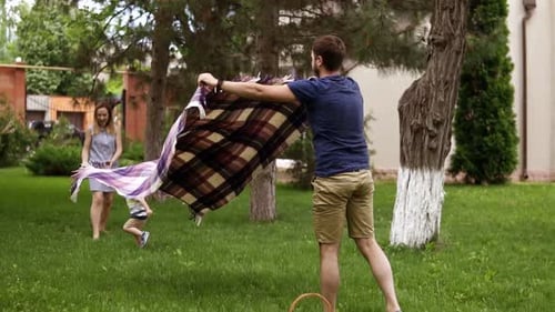 Family Sets Up Picnic Blanket on Green Lawn