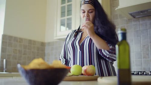 Woman Cuts and Tastes Fruit in Bright Kitchen