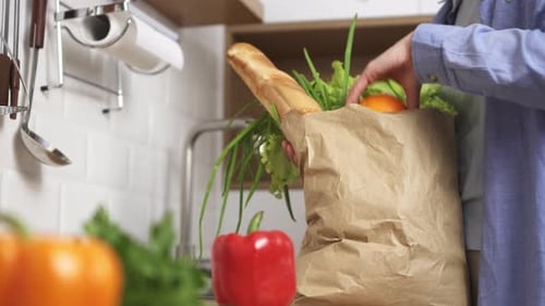 El vegetariano pone comida sobre la mesa. La niña llegó a casa con las compras, una bolsa ecológica de papel con verduras