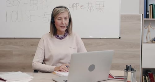 Mature Woman Teaching Online Class at Desk