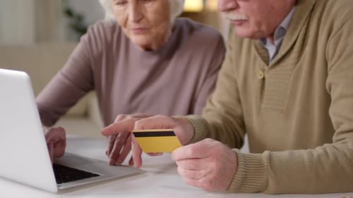 Seniors Using Laptop With Credit Card Indoors