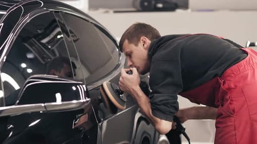 Man Buffing Black Car with Polishing Tool