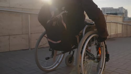 Person in Wheelchair Moves Along City Sidewalk