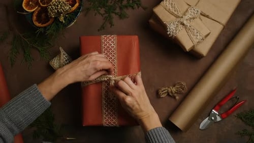 Hands Tying Ribbon on Christmas Gift Flat Lay
