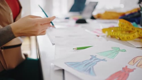 Gros plan d'un créateur de mode gaucher dessinant des croquis travaillant à l'atelier de tailleur