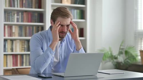 Man Reacting to Loss While Using Laptop in Office