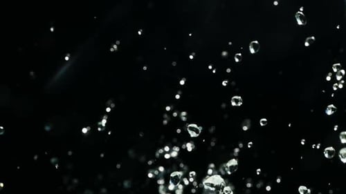 Aufnahmen von steigenden und fallenden Drops in Zeitlupe auf schwarzem Hintergrund. Fallende kochende Wassertröpfchen