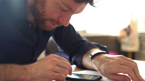 Adult Man Using Phone and Smartwatch at Desk