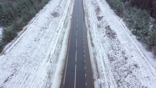 Winter highway, car and truck traffic. On the sides of the forest.
