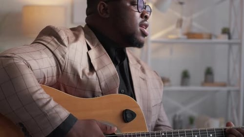 Man Plays Acoustic Guitar and Sings Indoors