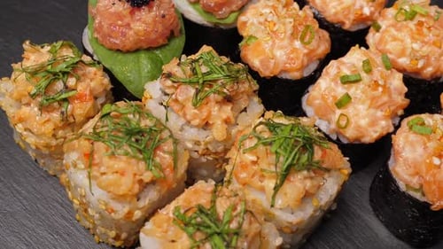 Sushi Rolls Set Rotating on Black Slate Board