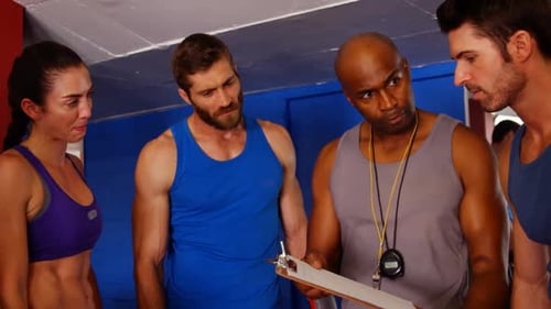 Fitness Instructor Discussing Plans with Group in Gym