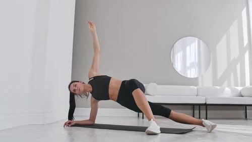 Slender Woman Performing Yoga Side Plank Indoors