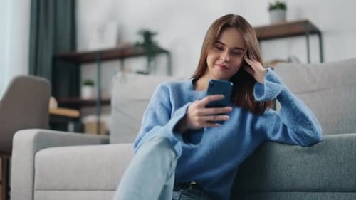 Young Woman Relaxing with Smartphone on Couch Indoors